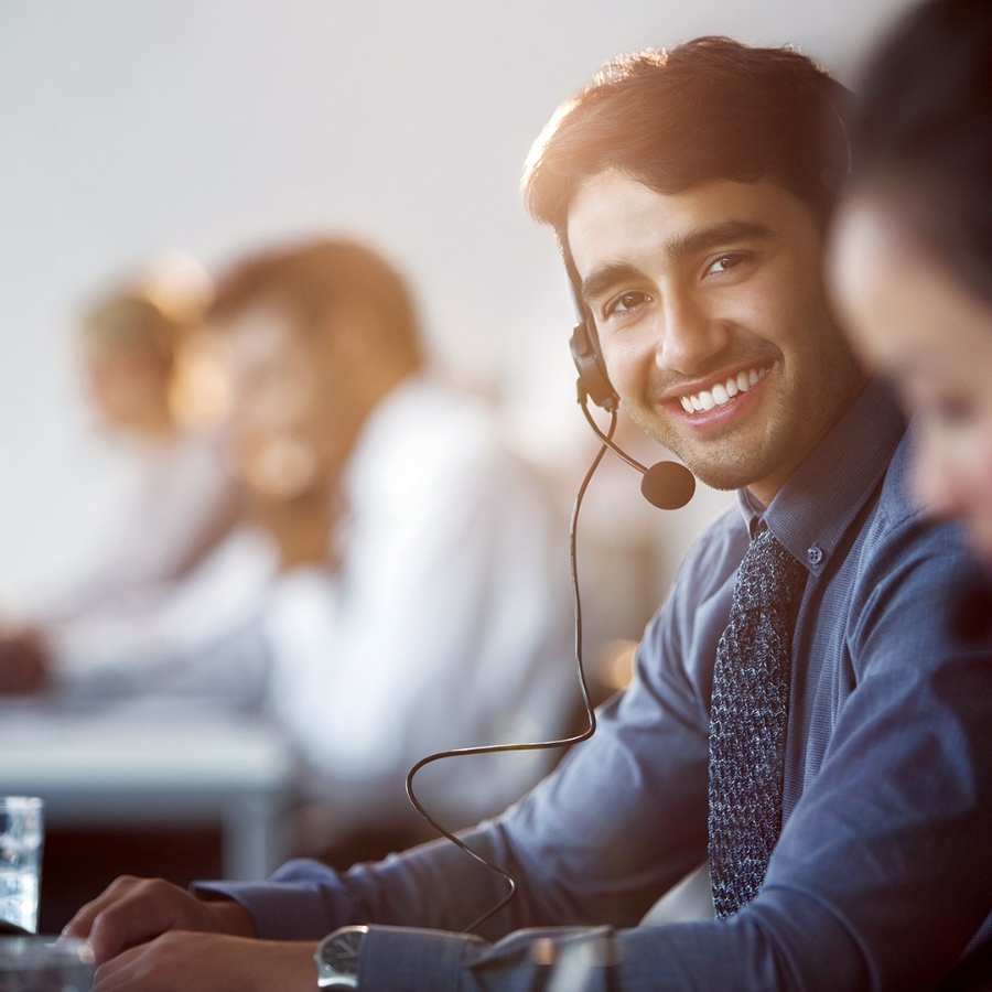 Male customer support representative wearing headset and smiling while facing camera