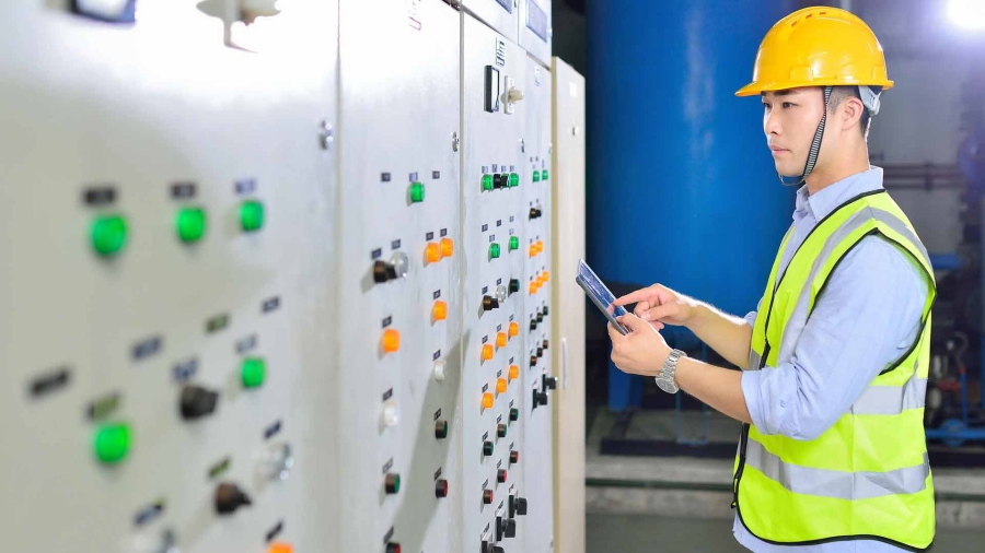 a young man in protective workwear working at energy control room