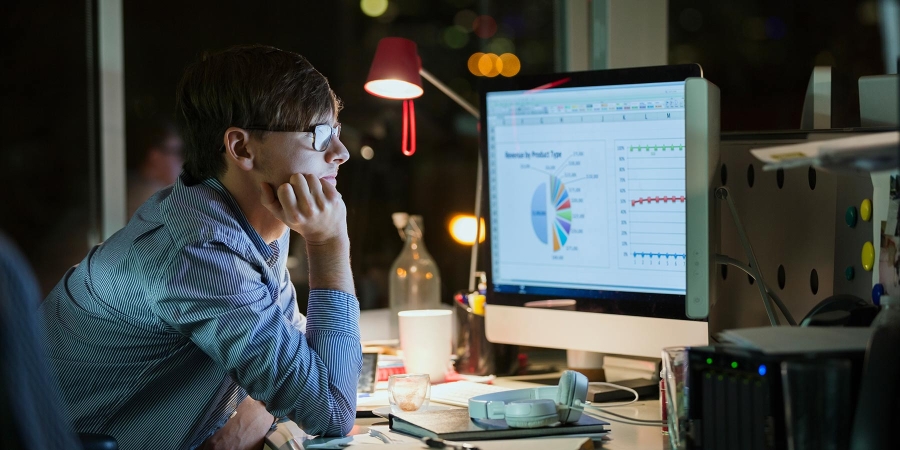 man wearing glasses analyzing pie chart on pc