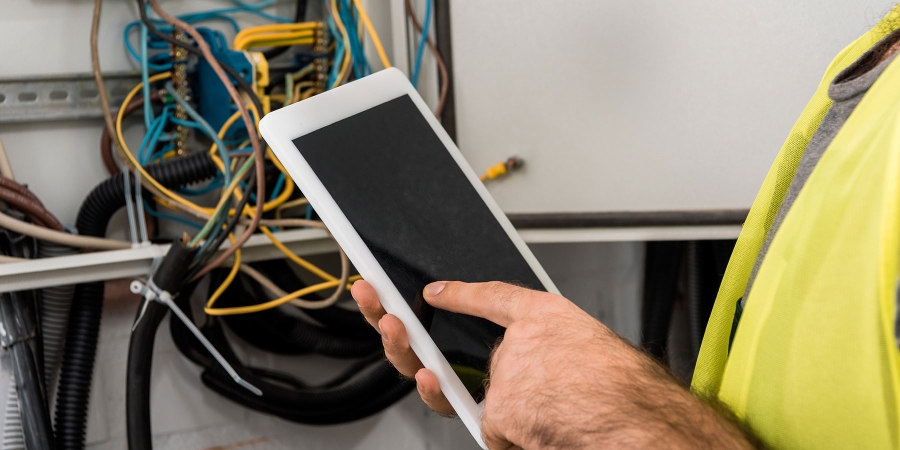 an electrician using a digital tablet near the electrical box