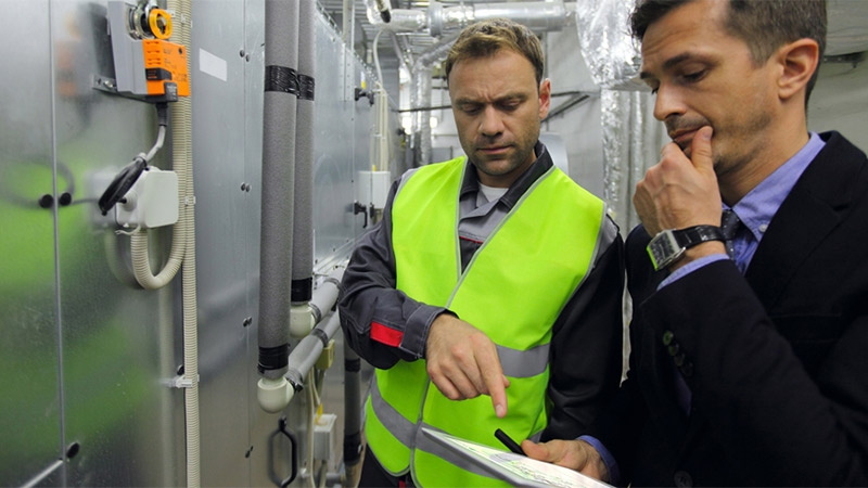 two men discussing machinery yellow jacket