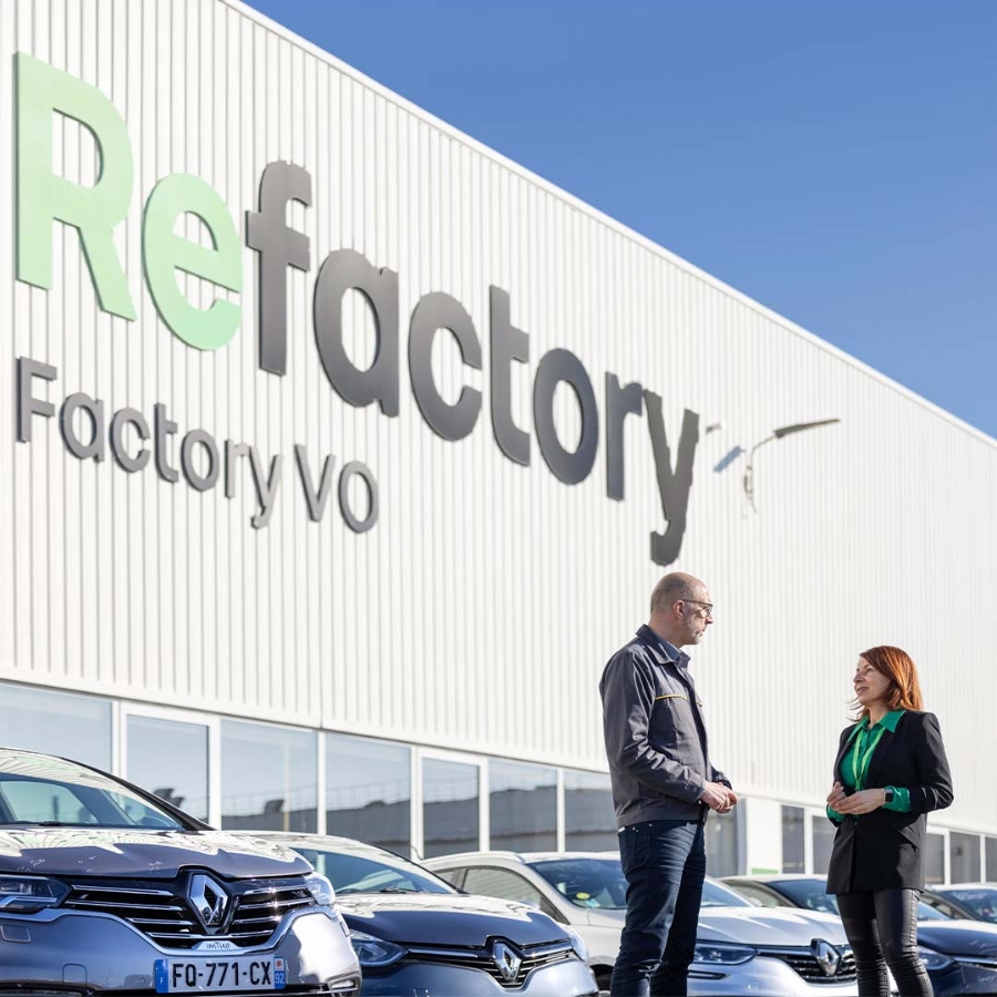 A person and person standing in front of a building with cars