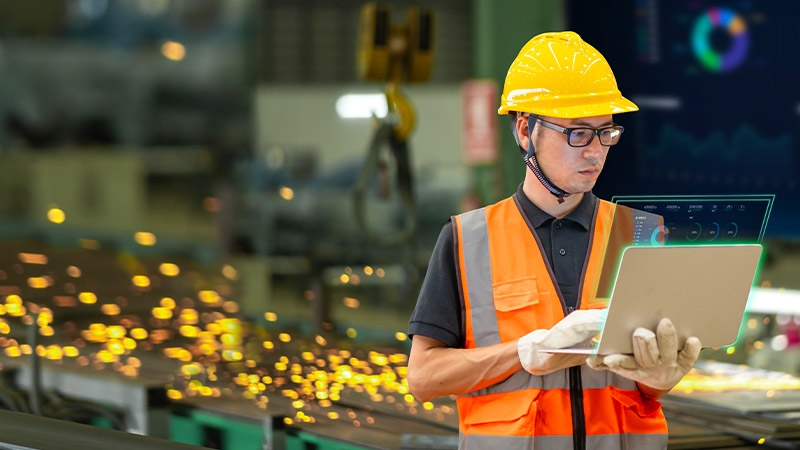 A man holding a computer in a factory