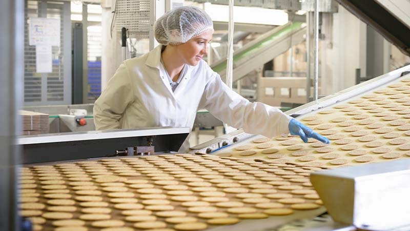 A person in a white coat working on a conveyor belt